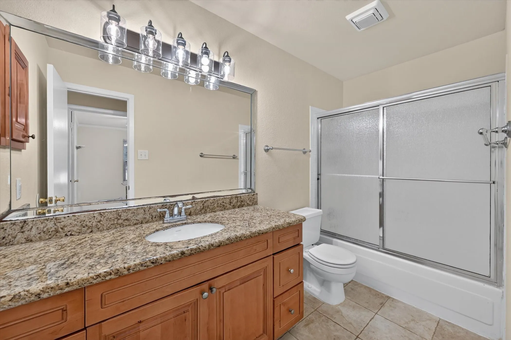 Vanity featuring a stone countertop, an undermount sink, and wood cabinetry with metal hardware