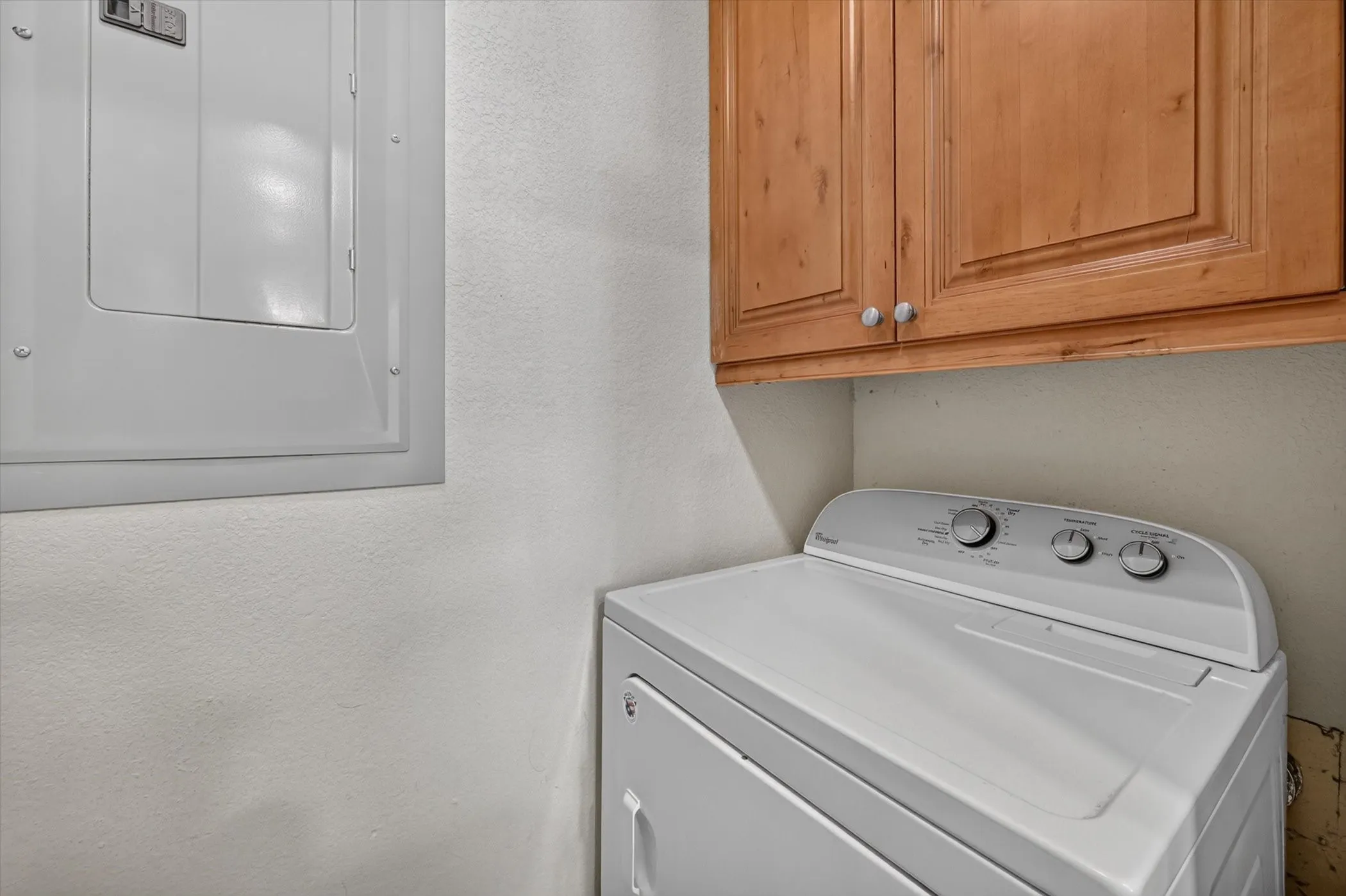 Dedicated laundry area featuring overhead wood-finish cabinetry