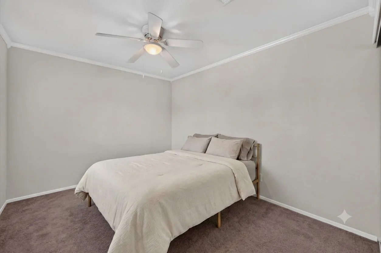 Bedroom featuring light neutral wall paint, white crown molding, and brown carpet flooring