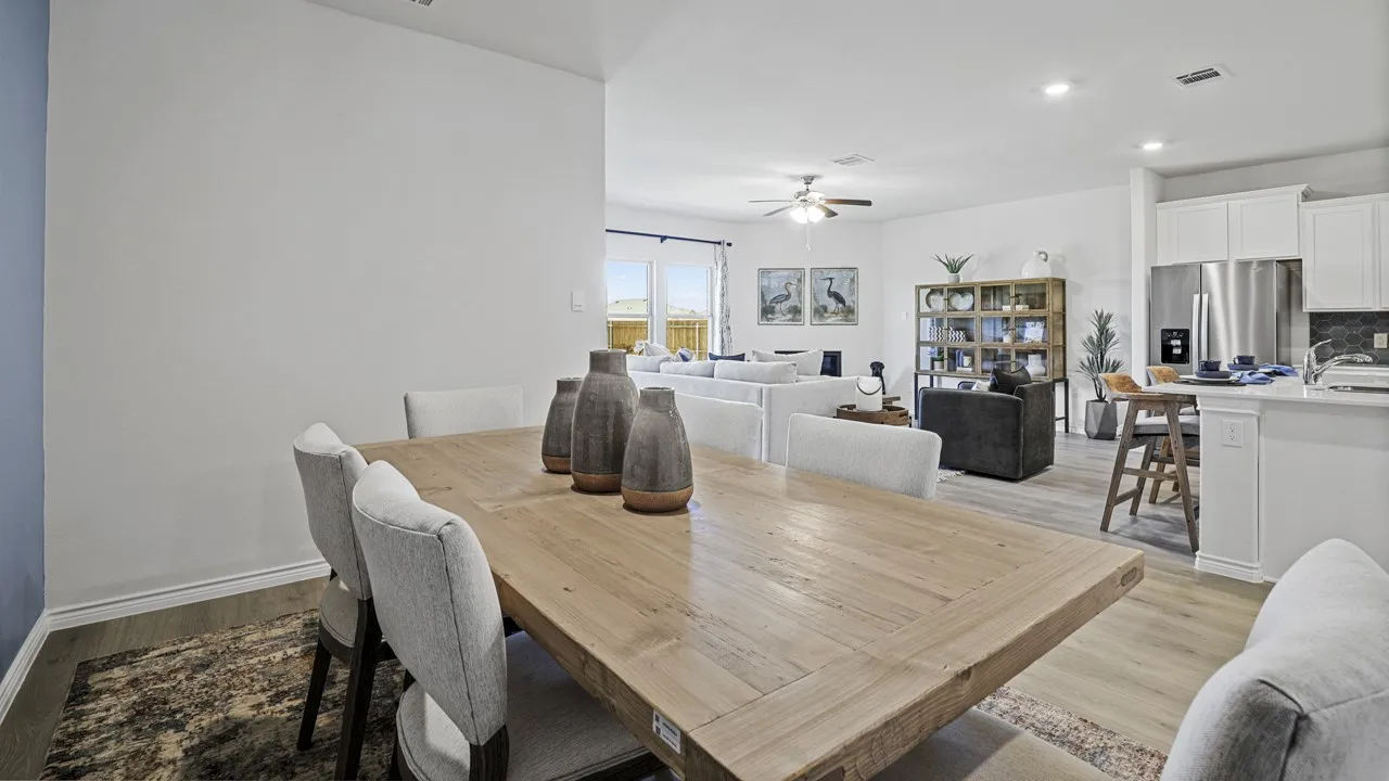 Open-concept living space featuring light wood-finish flooring, white walls, recessed lighting, and an integrated kitchen with white cabinetry and stainless steel appliances