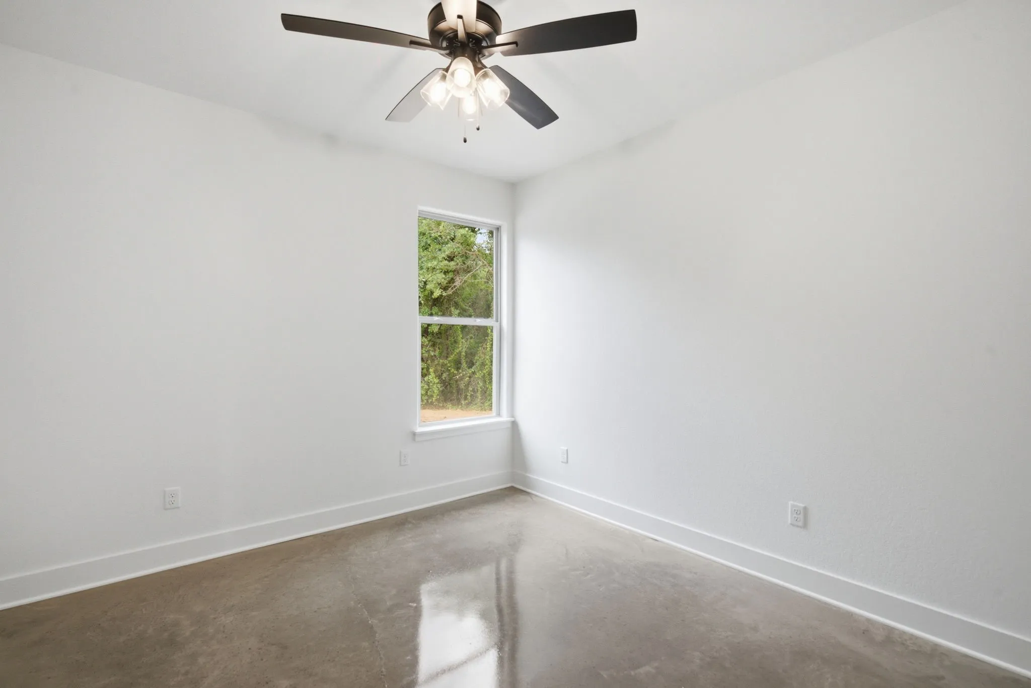 Bright interior space featuring polished concrete flooring, white walls, and a multi-blade ceiling fan with integrated lighting