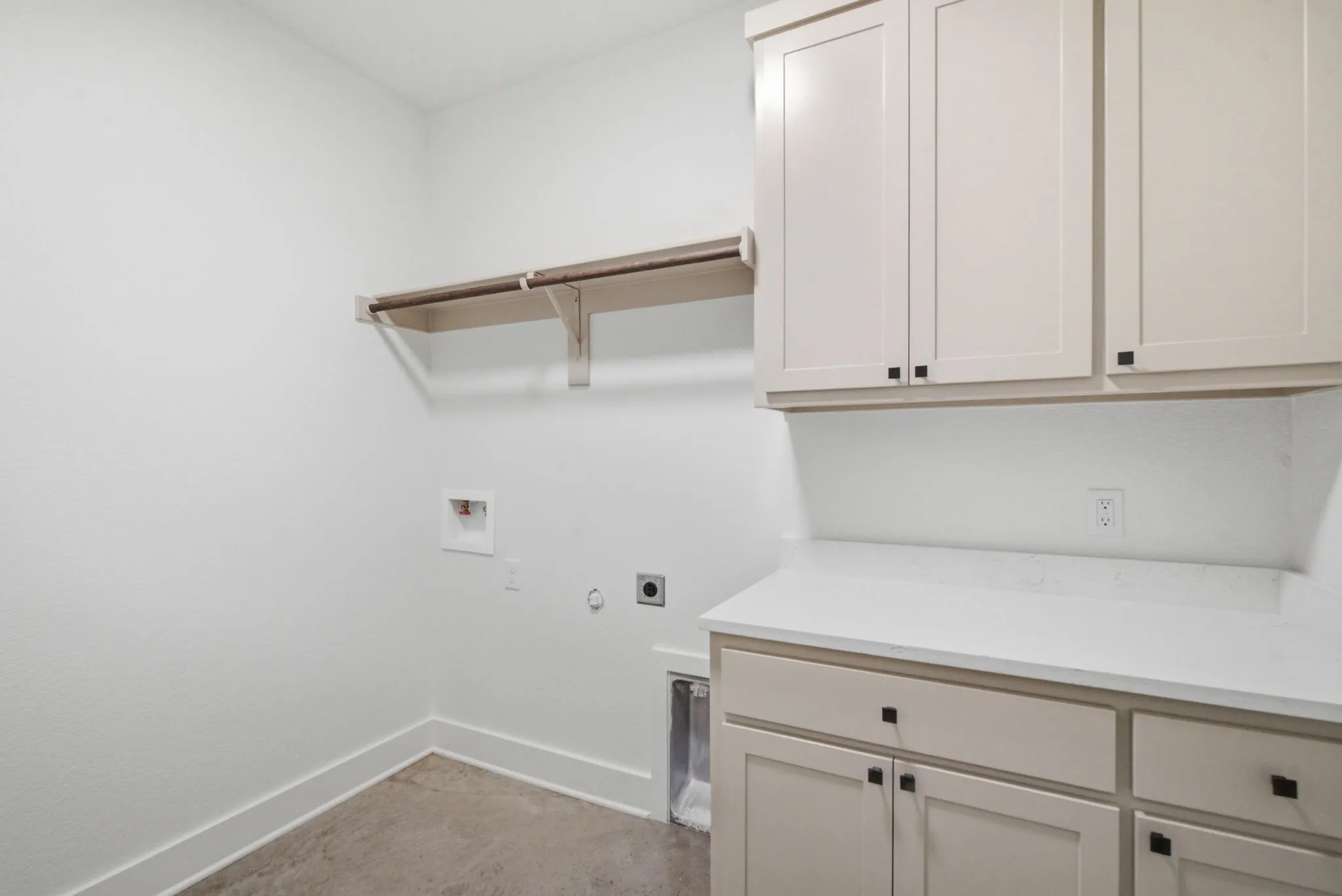 Laundry room featuring light-toned cabinetry, a spacious countertop, built-in shelving, and utility hookups
