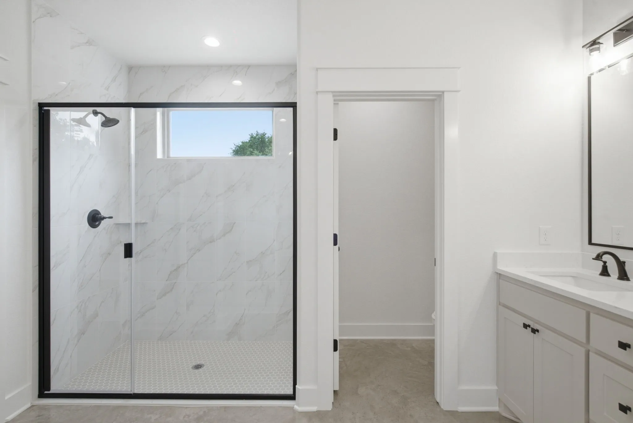 Walk-in shower with clear glass enclosure and matte black trim