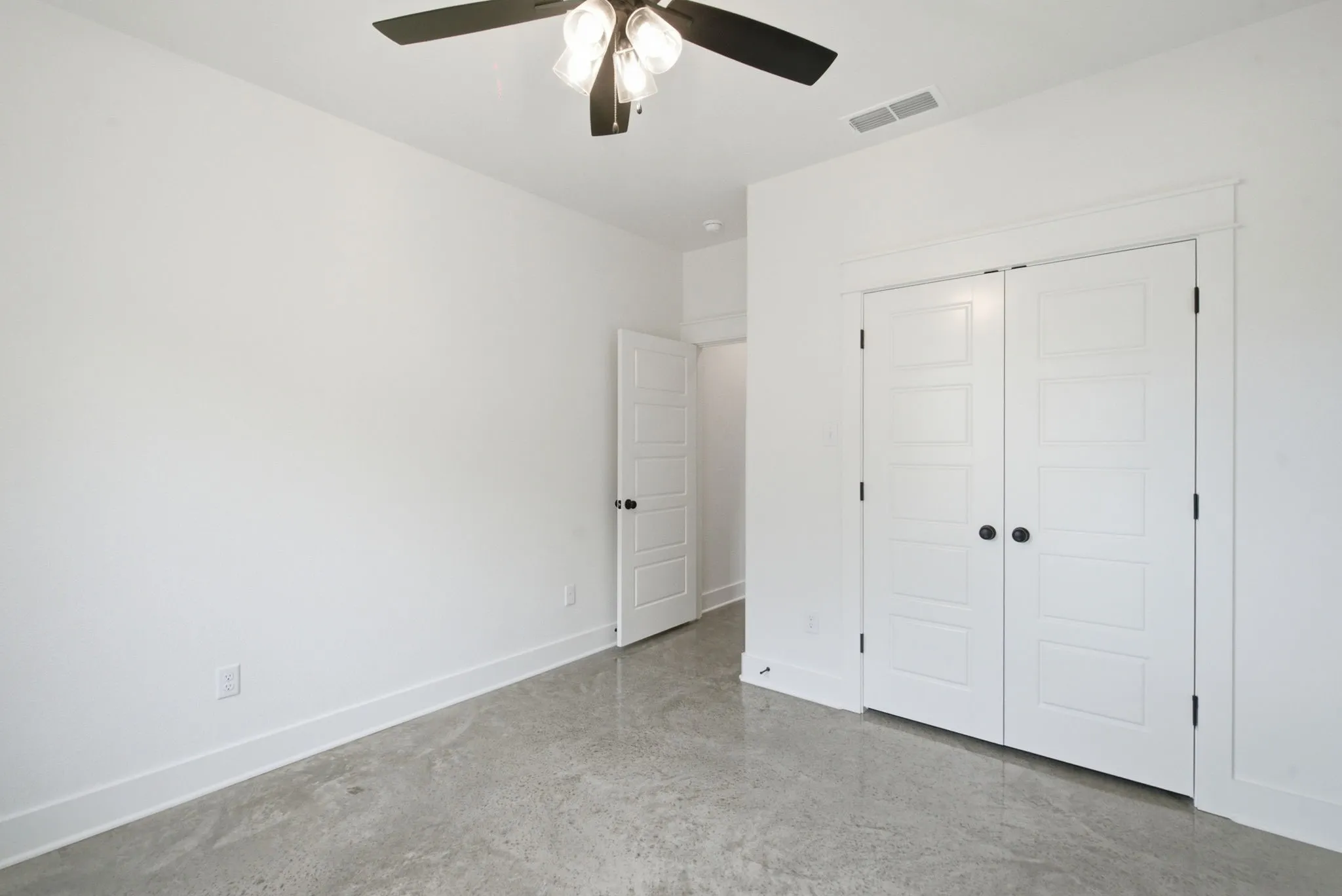 Concrete flooring with a modern ceiling fan and recessed lighting