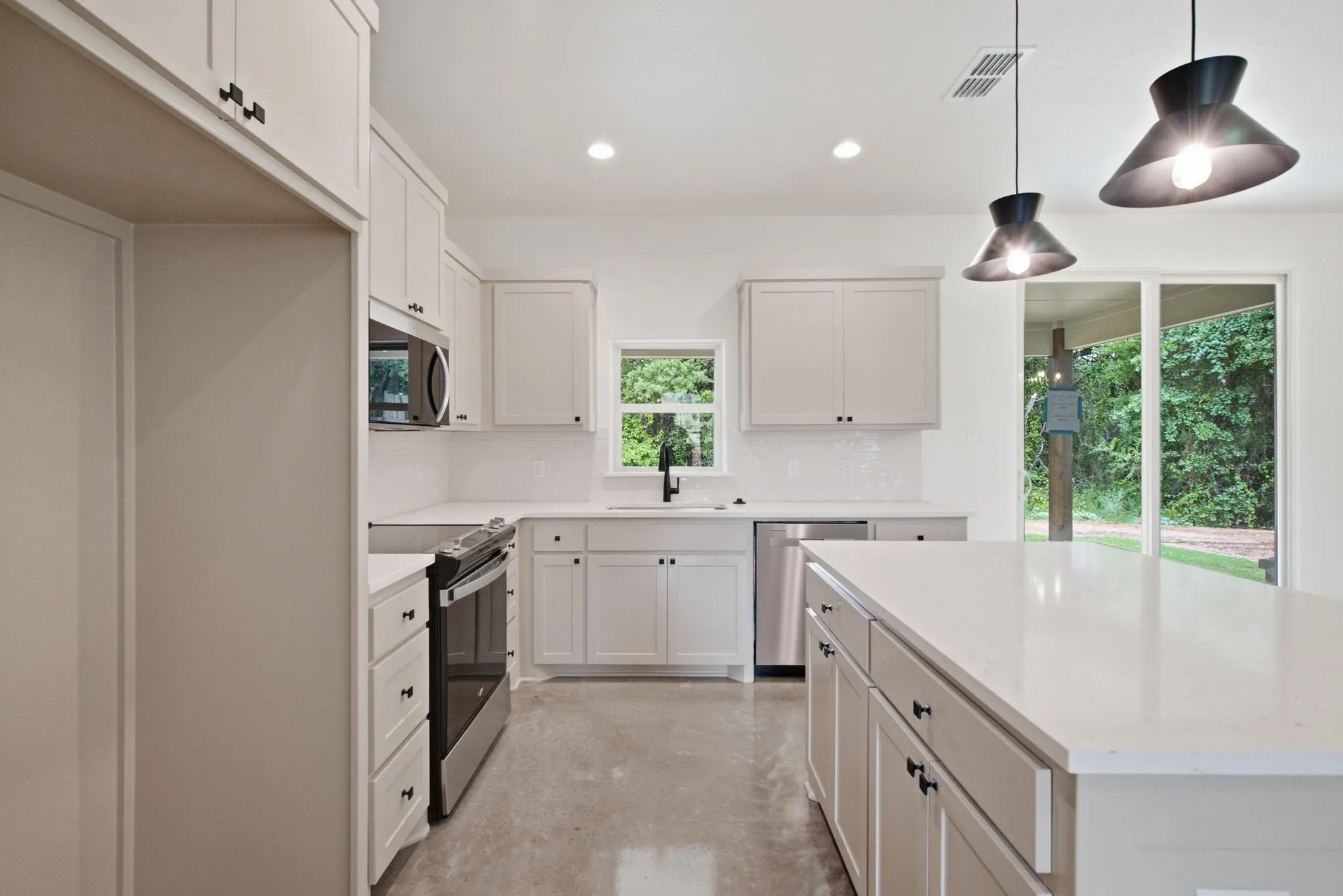 Modern kitchen featuring a large center island, light-toned cabinetry, stainless steel appliances, and white countertops