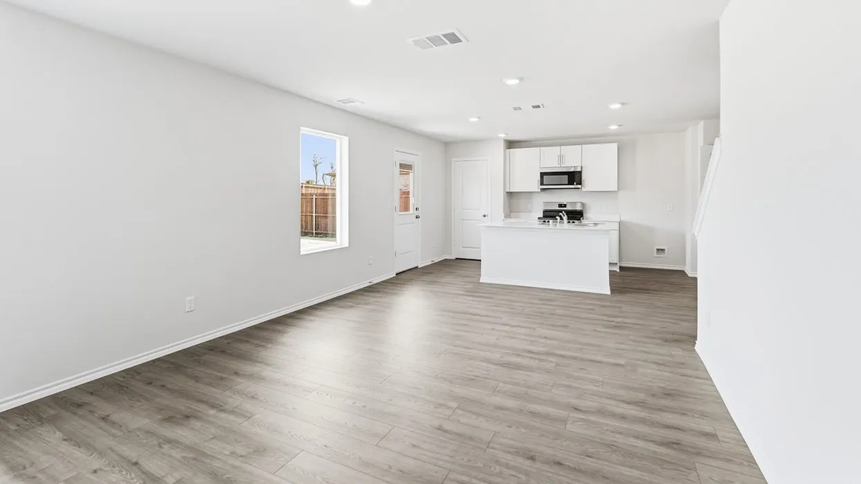 Open-concept living area featuring wood-finish flooring, recessed lighting, and a kitchen with white cabinetry, a kitchen island, and stainless steel appliances