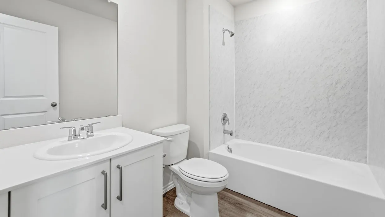 Full bathroom featuring a white vanity with an undermount sink, chrome fixtures, a full-width mirror, a white toilet, and a white tub with a textured surround