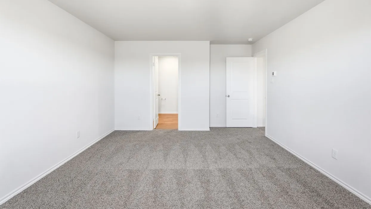 Spacious room featuring neutral gray carpet flooring and bright white walls