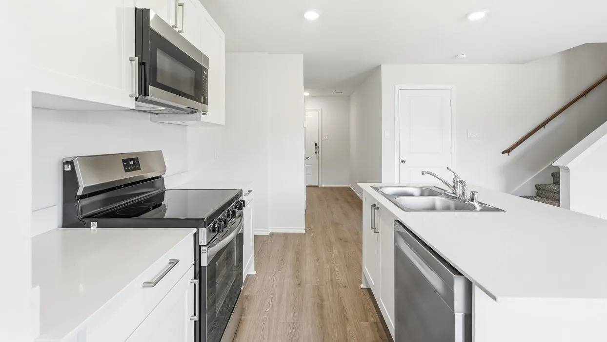 Kitchen featuring white cabinetry, stainless steel appliances, a double basin sink, and light-toned wood-finish flooring
