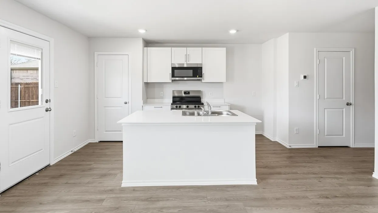 Modern kitchen featuring an island with an undermount double-basin sink, white cabinetry, integrated microwave, and stainless steel gas range