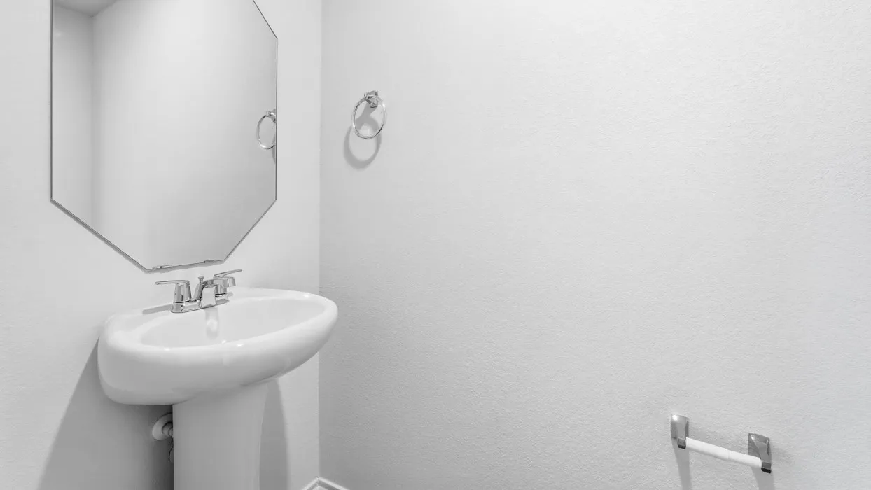 Pedestal sink with chrome faucet, complemented by an octagonal wall mirror