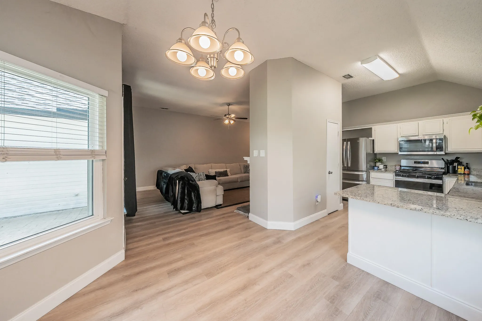 Kitchen island with a light-colored countertop, white cabinetry, stainless steel appliances, and a gas range