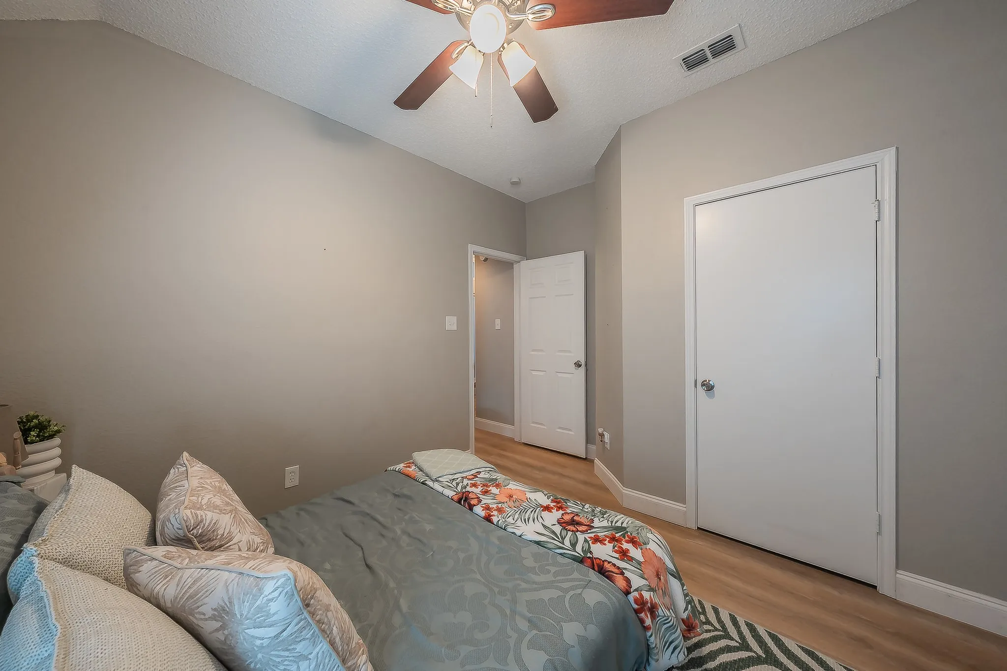 Room featuring neutral wall tones, wood-finish flooring, and a ceiling fan with integrated lighting