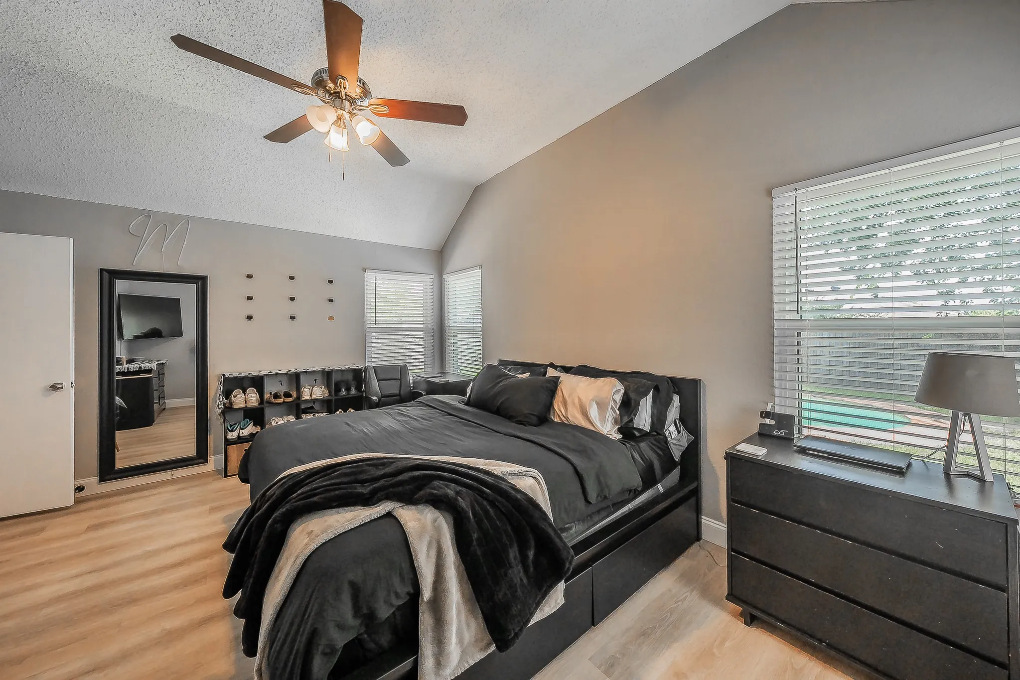 Bedroom featuring vaulted ceilings, wood-finish flooring, and a ceiling fan with light fixture
