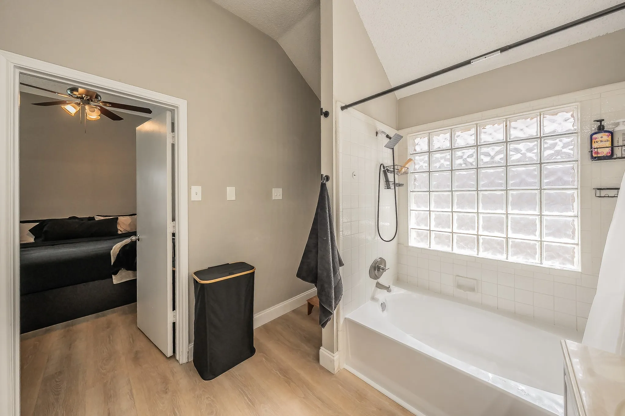 Bathroom featuring a glass block window, white subway tile surround, and a tub with an integrated shower