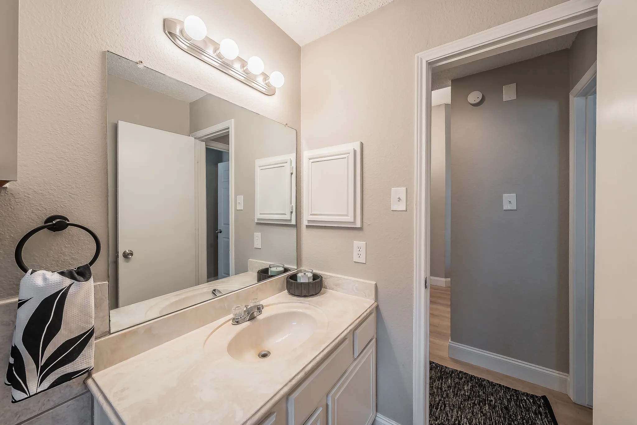 Bathroom vanity featuring an integrated sink, polished chrome faucet, and a large wall-mounted mirror
