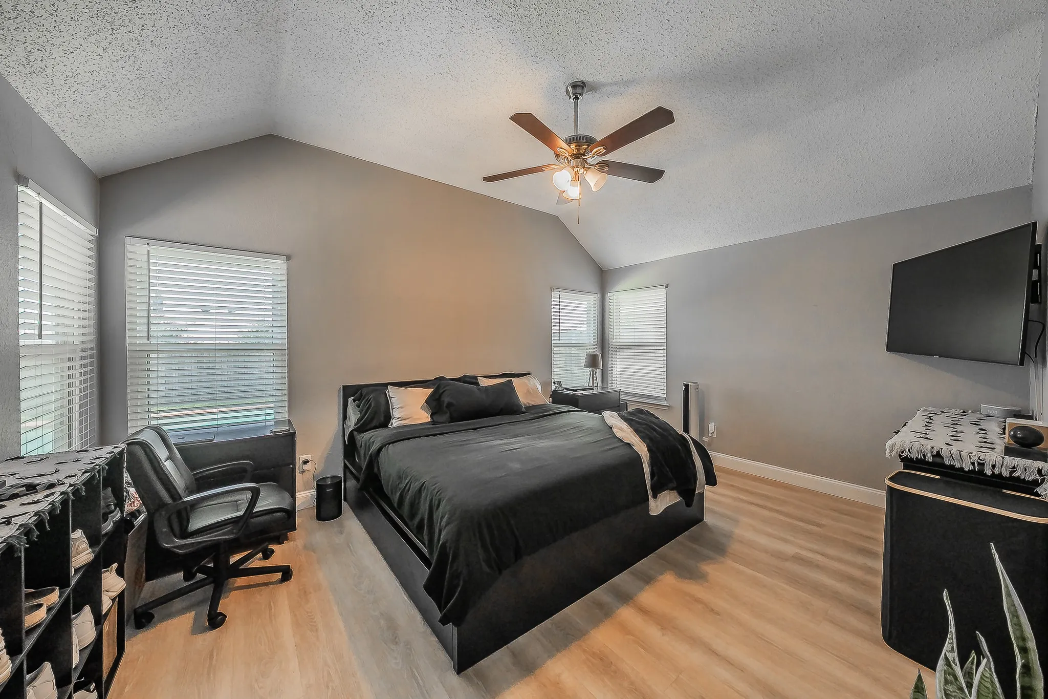Vaulted ceiling bedroom with light wood-finish flooring
