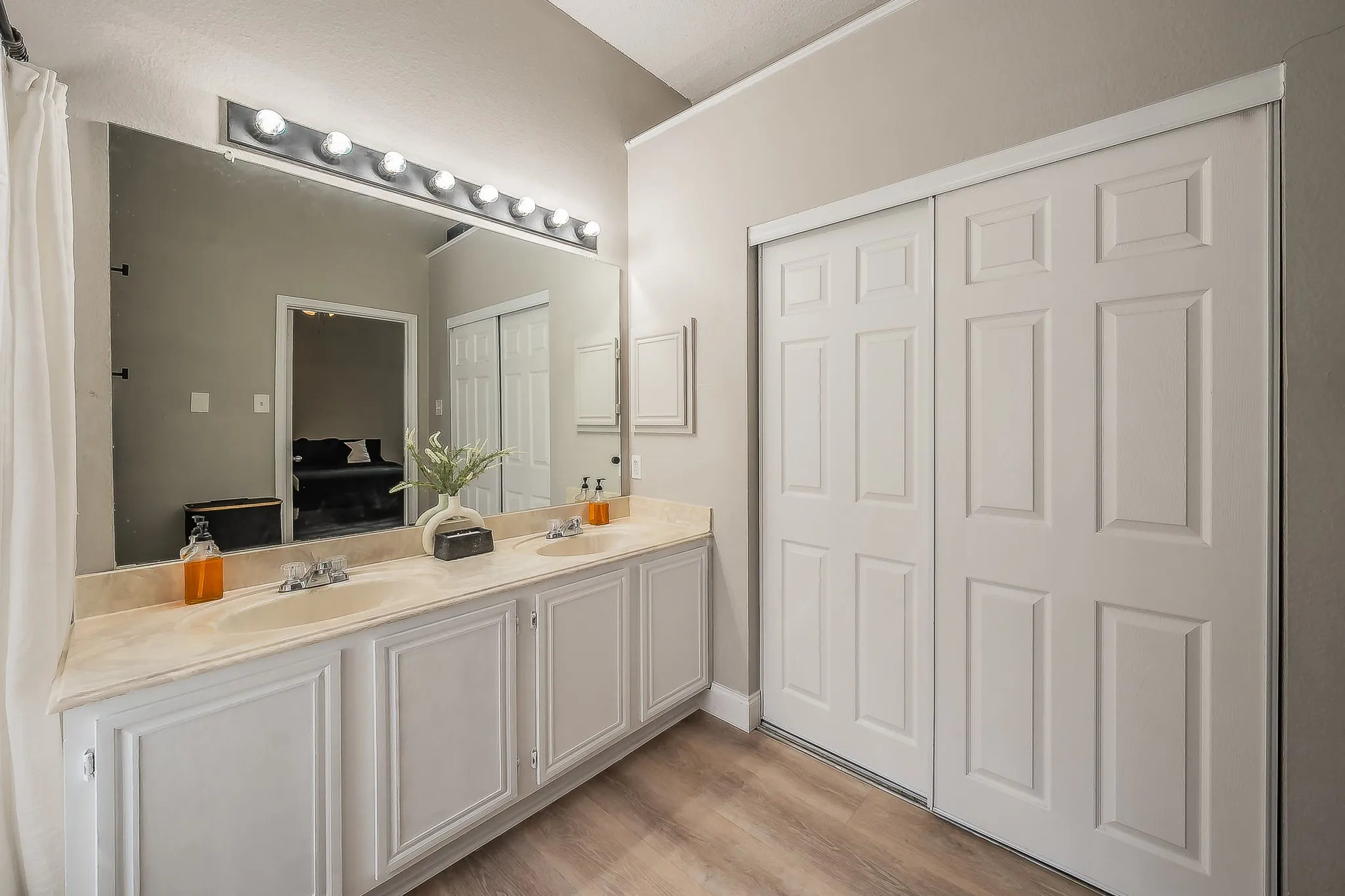Bathroom featuring a double vanity with two undermount sinks, a light-colored countertop, and white cabinetry