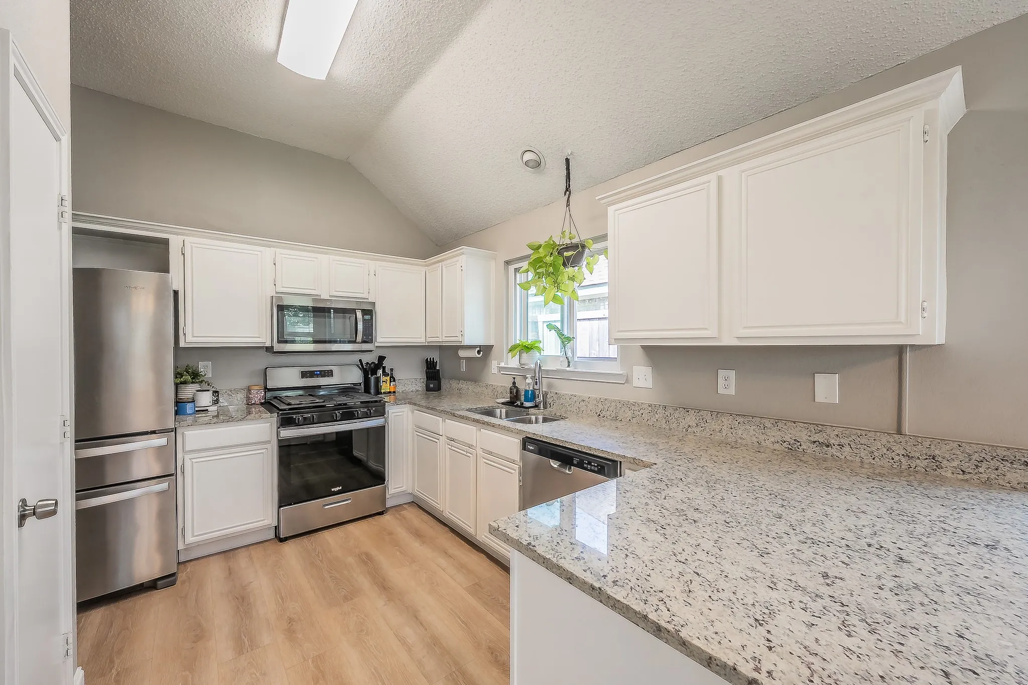 Kitchen featuring white cabinetry, light-toned granite countertops, and stainless steel appliances