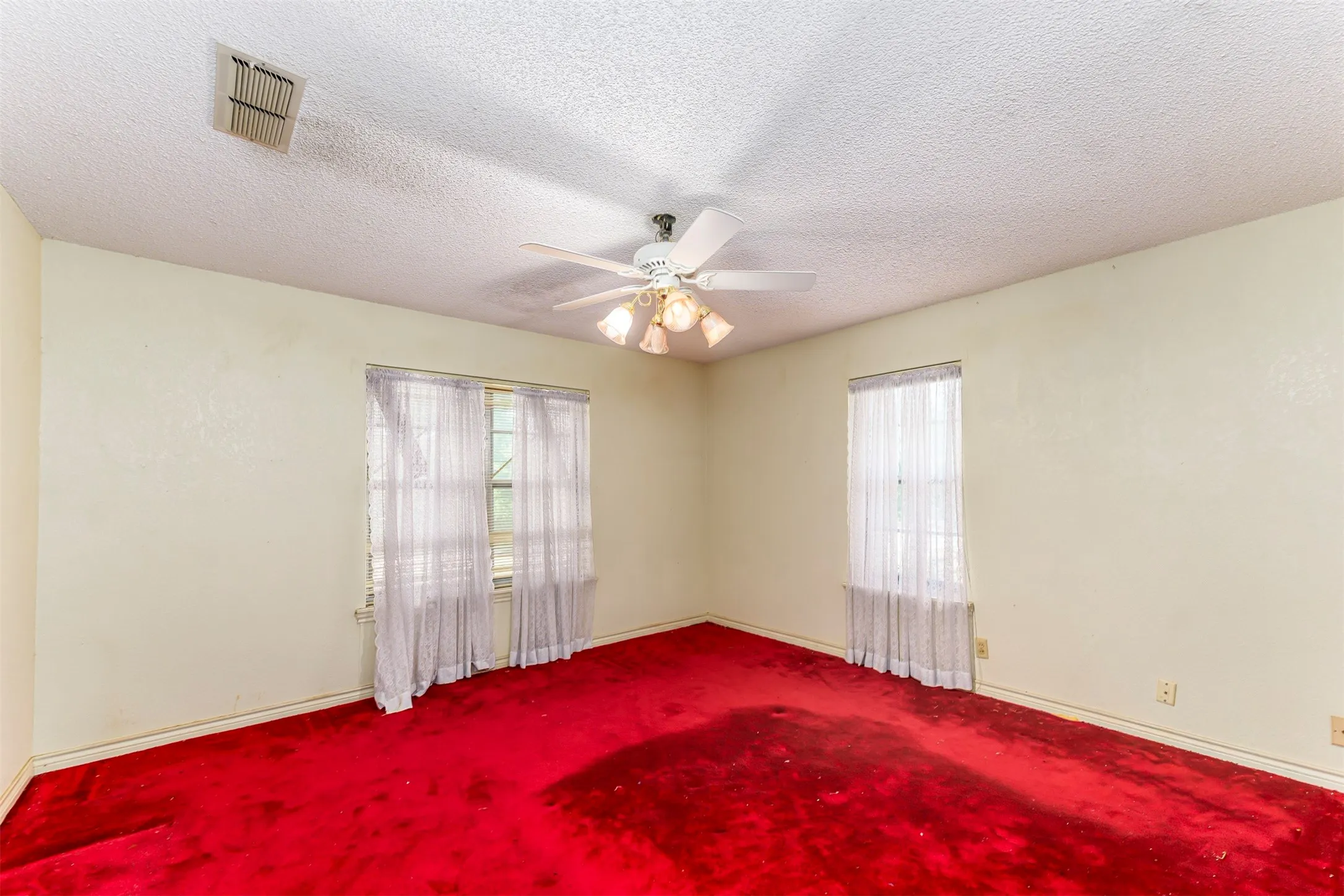 Room featuring red carpeting, light-colored walls, and a textured ceiling