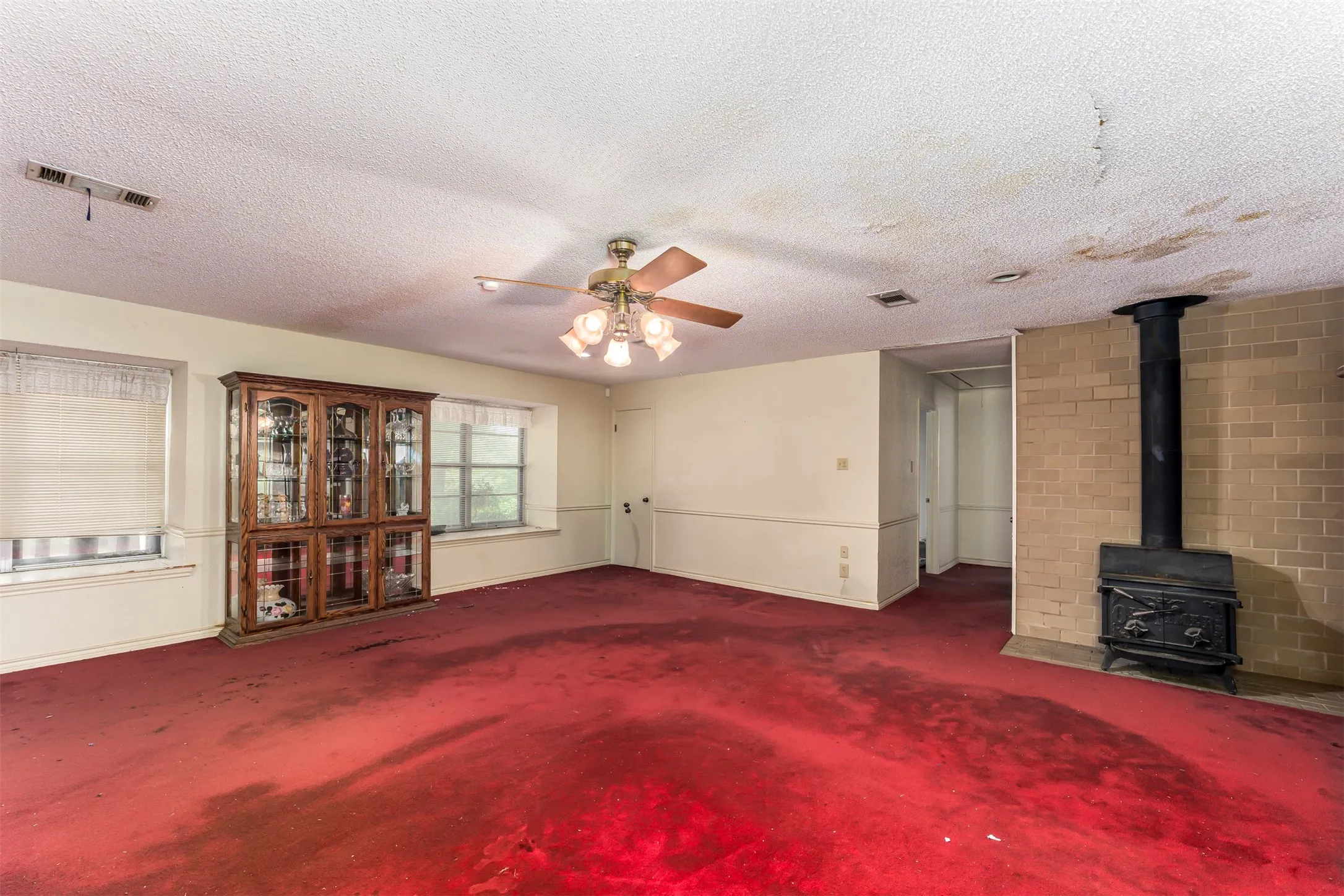 Living area featuring a brick hearth with a black wood-burning stove and a ceiling fan with light fixture