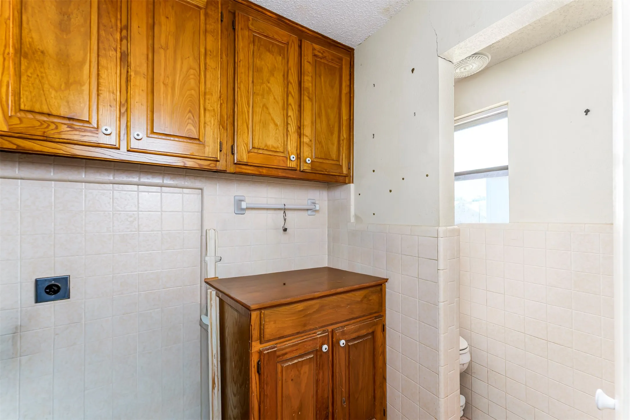 Upper cabinetry with wood-finish doors, a tiled backsplash, and a wood-finish base cabinet