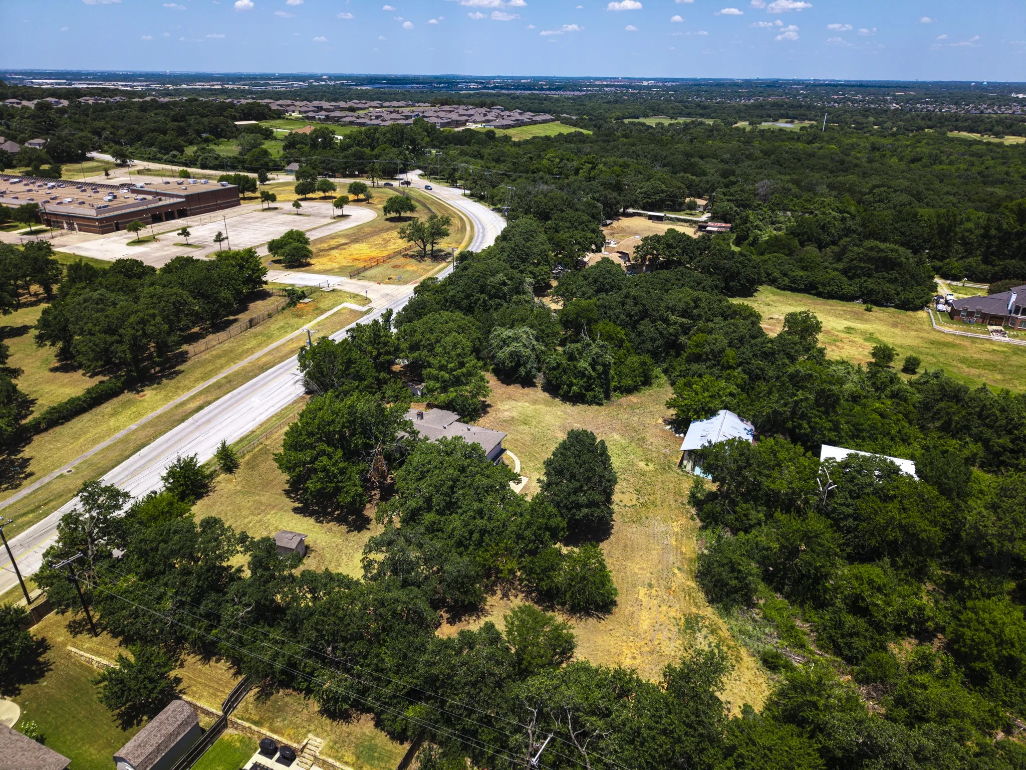 Expansive aerial showcasing a verdant landscape with mature trees and open grassy areas