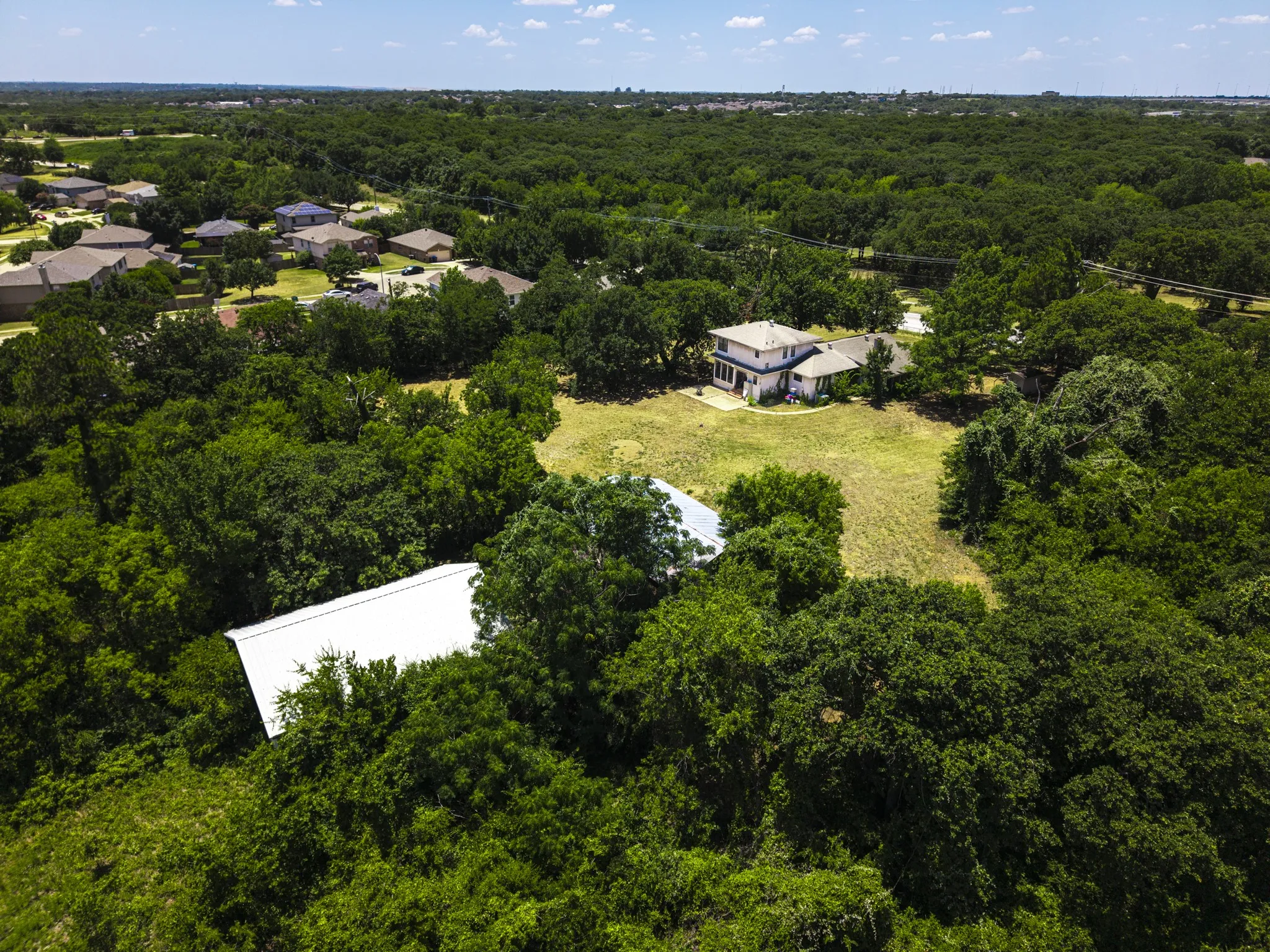 Spacious property featuring a large residence, expansive green space, and a separate outbuilding with a metal roof