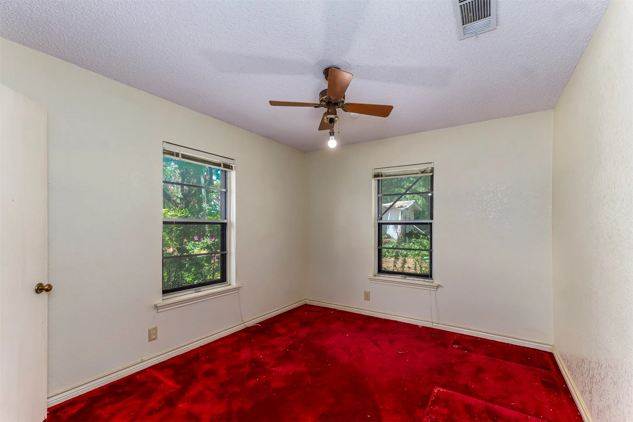 Room featuring two windows, red carpeting, a white ceiling with a ceiling fan, and light-colored walls