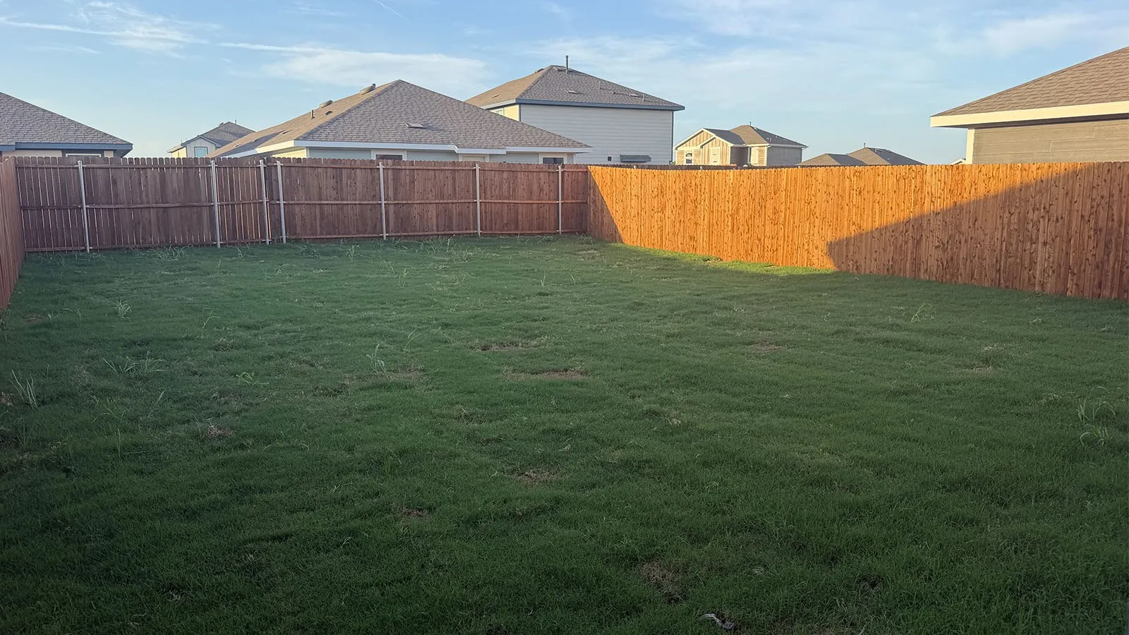 Expansive backyard featuring a privacy fence and a green lawn