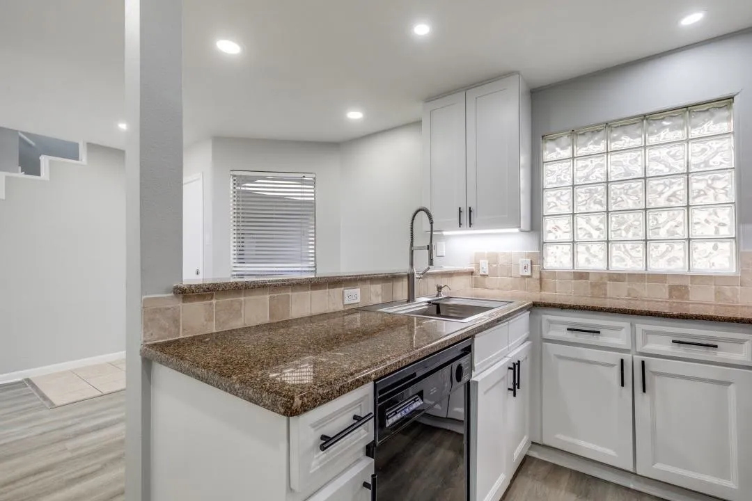 Contemporary kitchen featuring granite countertops and white cabinetry