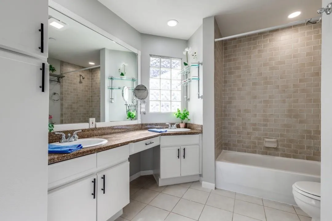 Dual vanity with white cabinetry, dark countertops, and undermount sinks