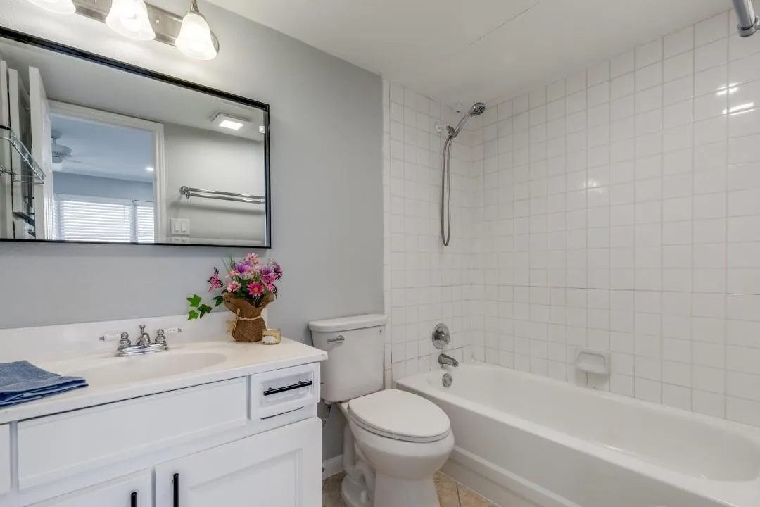 Bathroom featuring a white vanity with integrated sink, white subway tile shower surround, and a tub with a handheld shower fixture