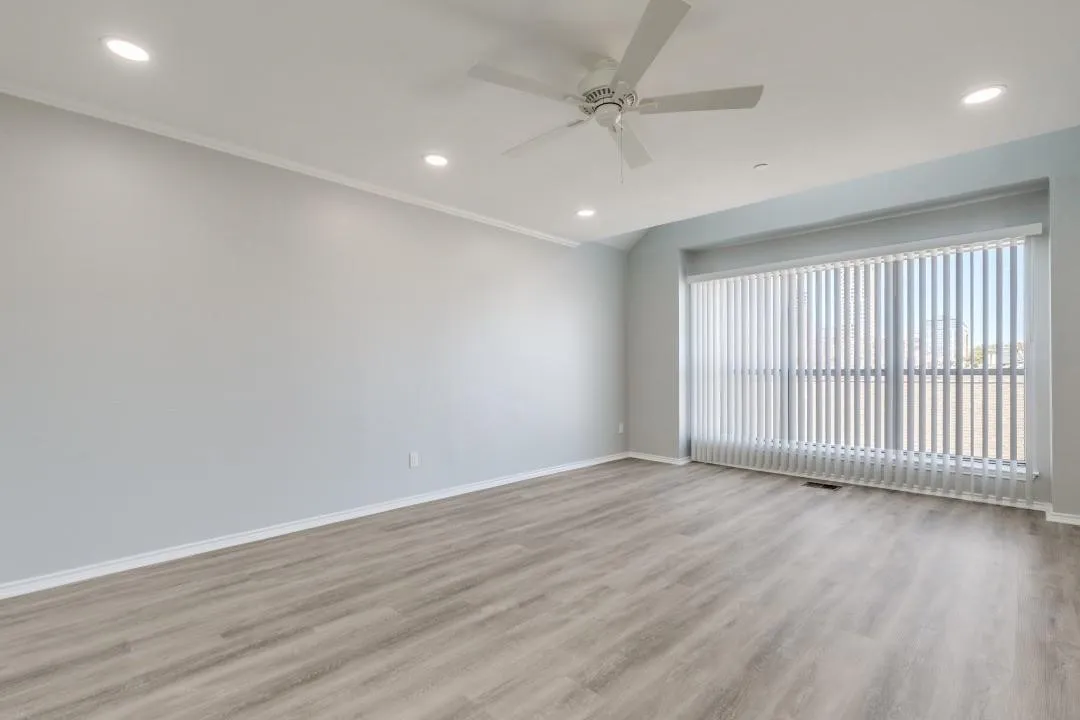 Spacious room featuring wood-finish flooring, recessed lighting, and a ceiling fan