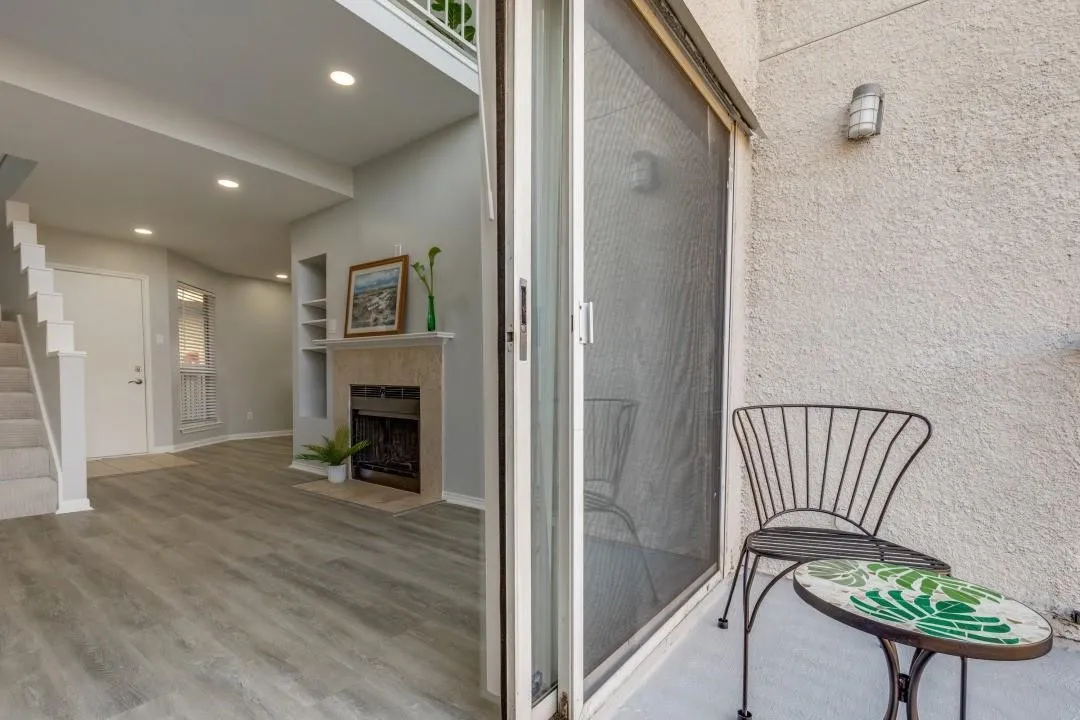 Spacious living area featuring wood-finish flooring, a fireplace with a stone surround, and recessed lighting