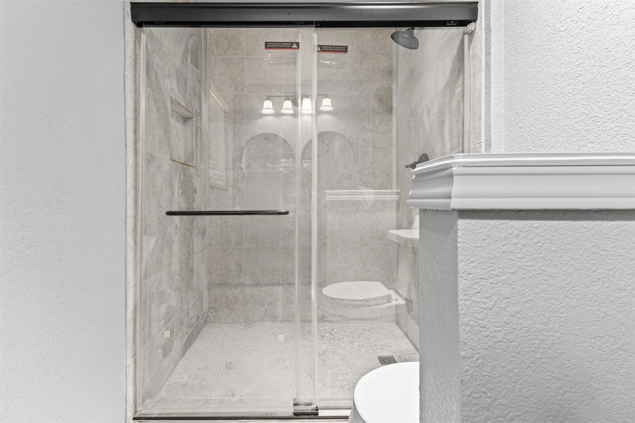 Glass-enclosed shower featuring tiled walls, a built-in niche, and a rain showerhead