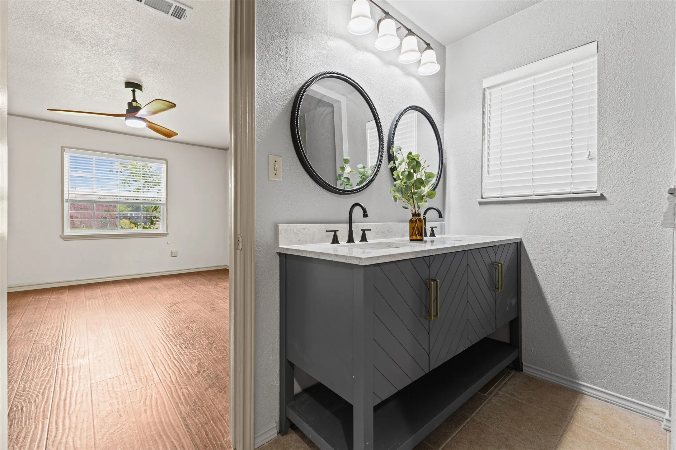 Dual vanity with round mirrors, matte black fixtures, and a light-toned countertop