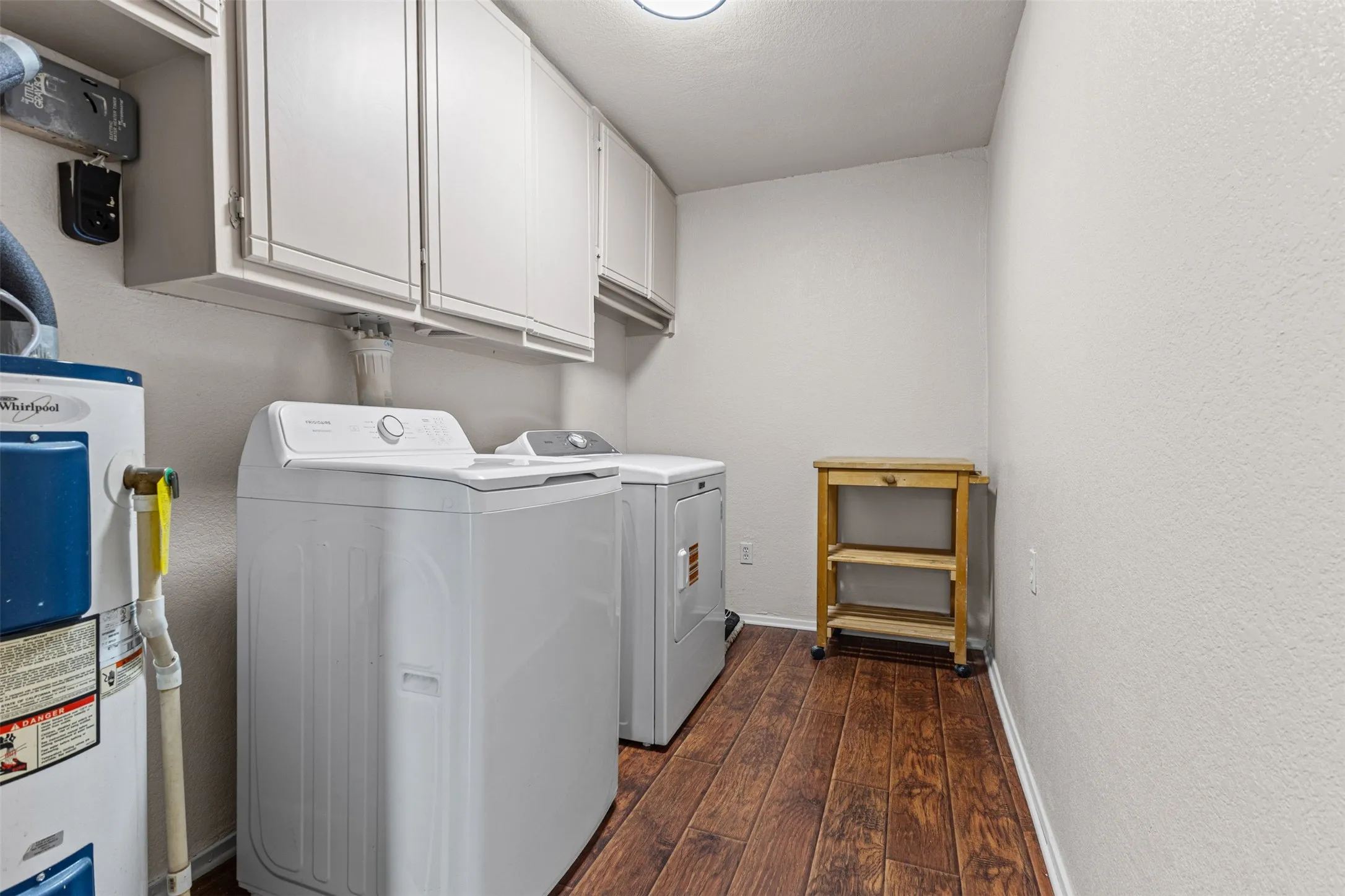 Dedicated laundry area featuring wood-finish flooring, white wall cabinetry, and neutral wall tones