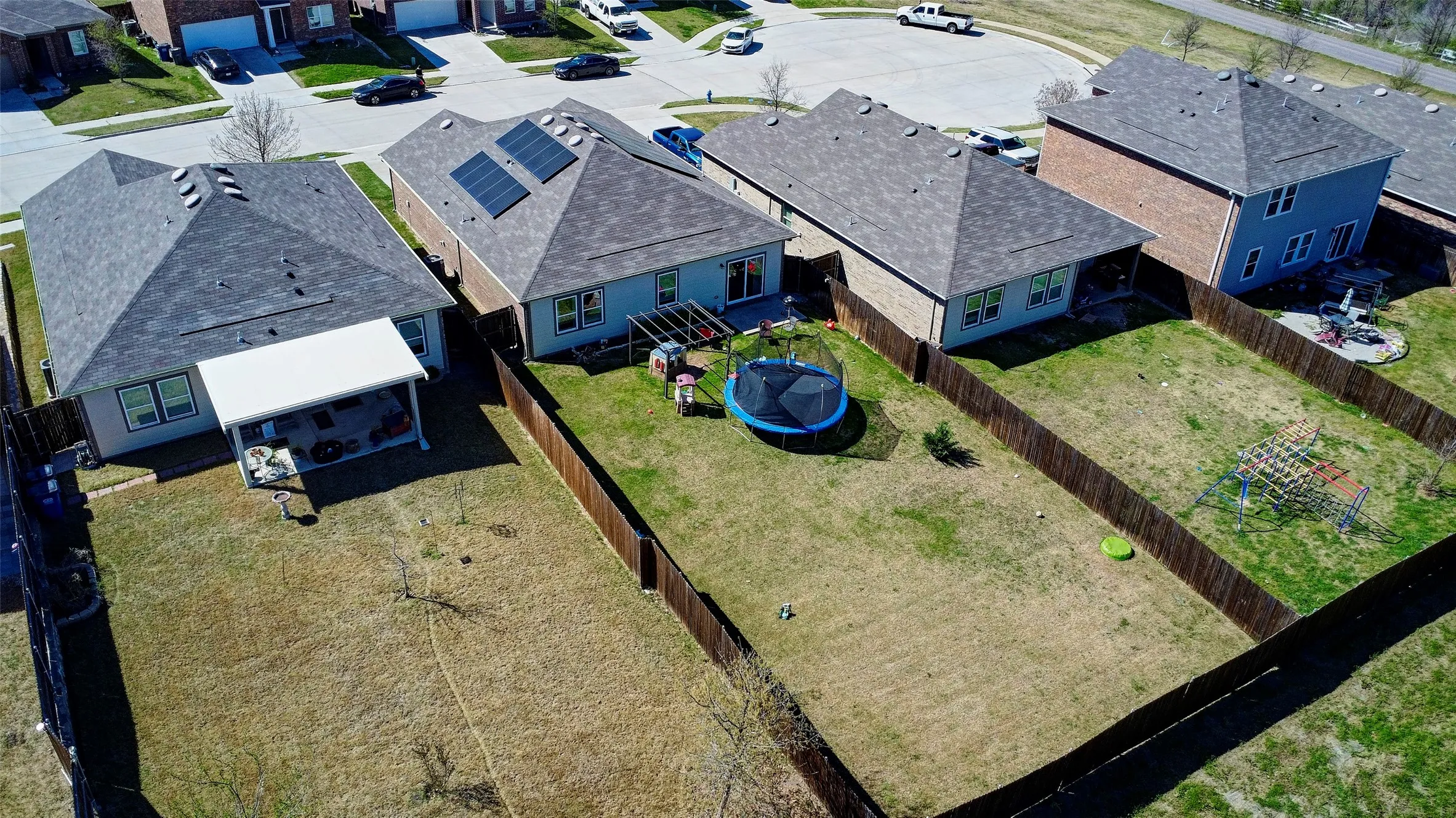 Expansive backyard featuring a wood privacy fence, a covered patio, and a shingled roof
