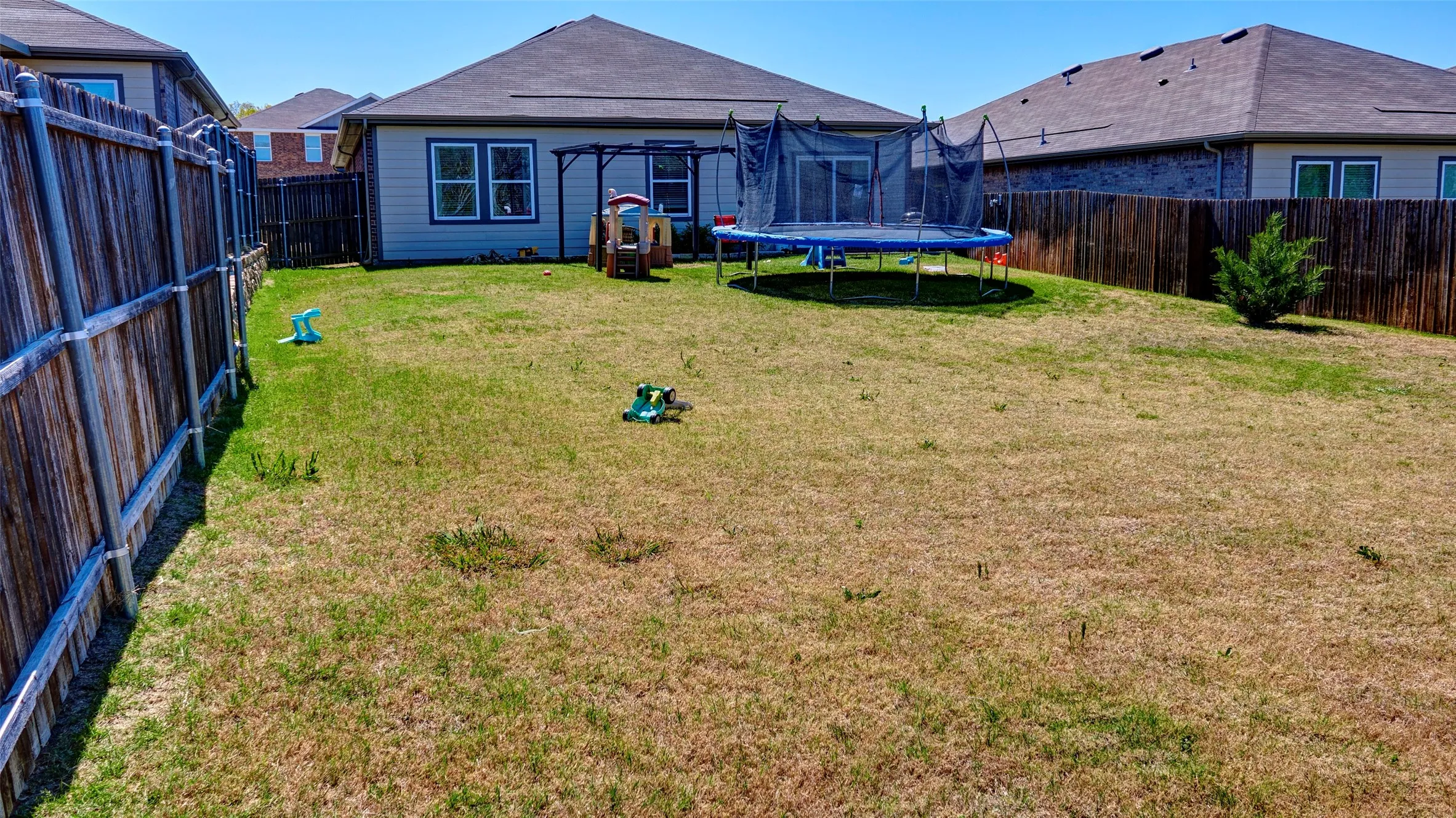 Expansive backyard featuring a privacy fence and a rear exterior with a sliding glass door