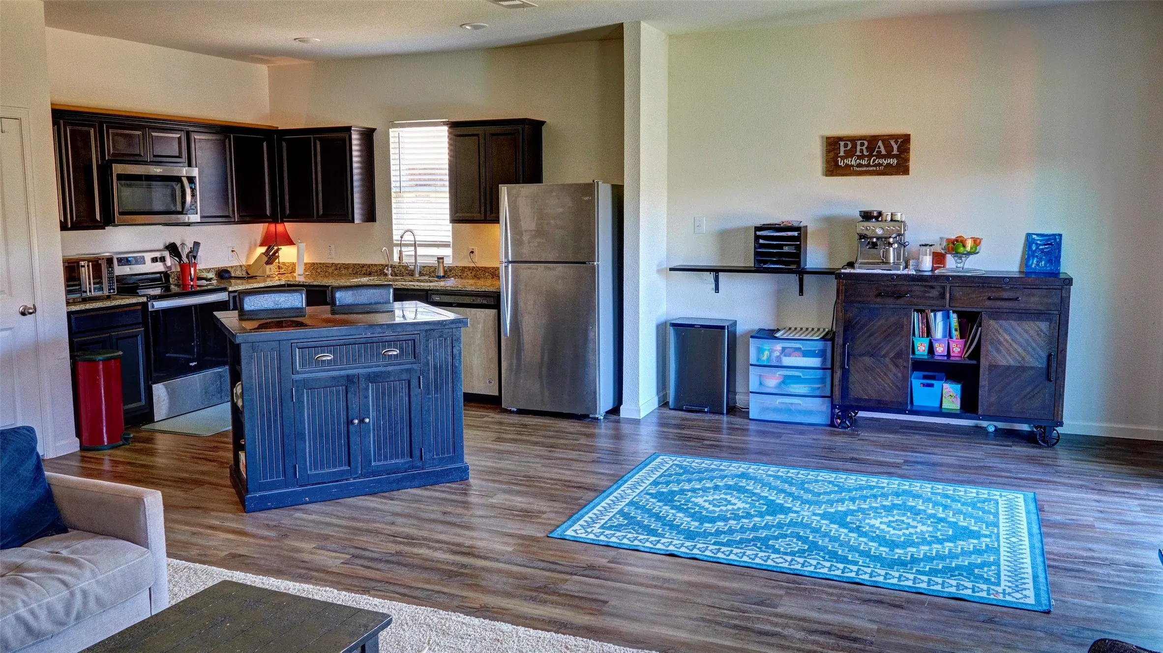 Open-concept kitchen with dark wood-finish cabinetry, stainless steel appliances, and wood-finish flooring