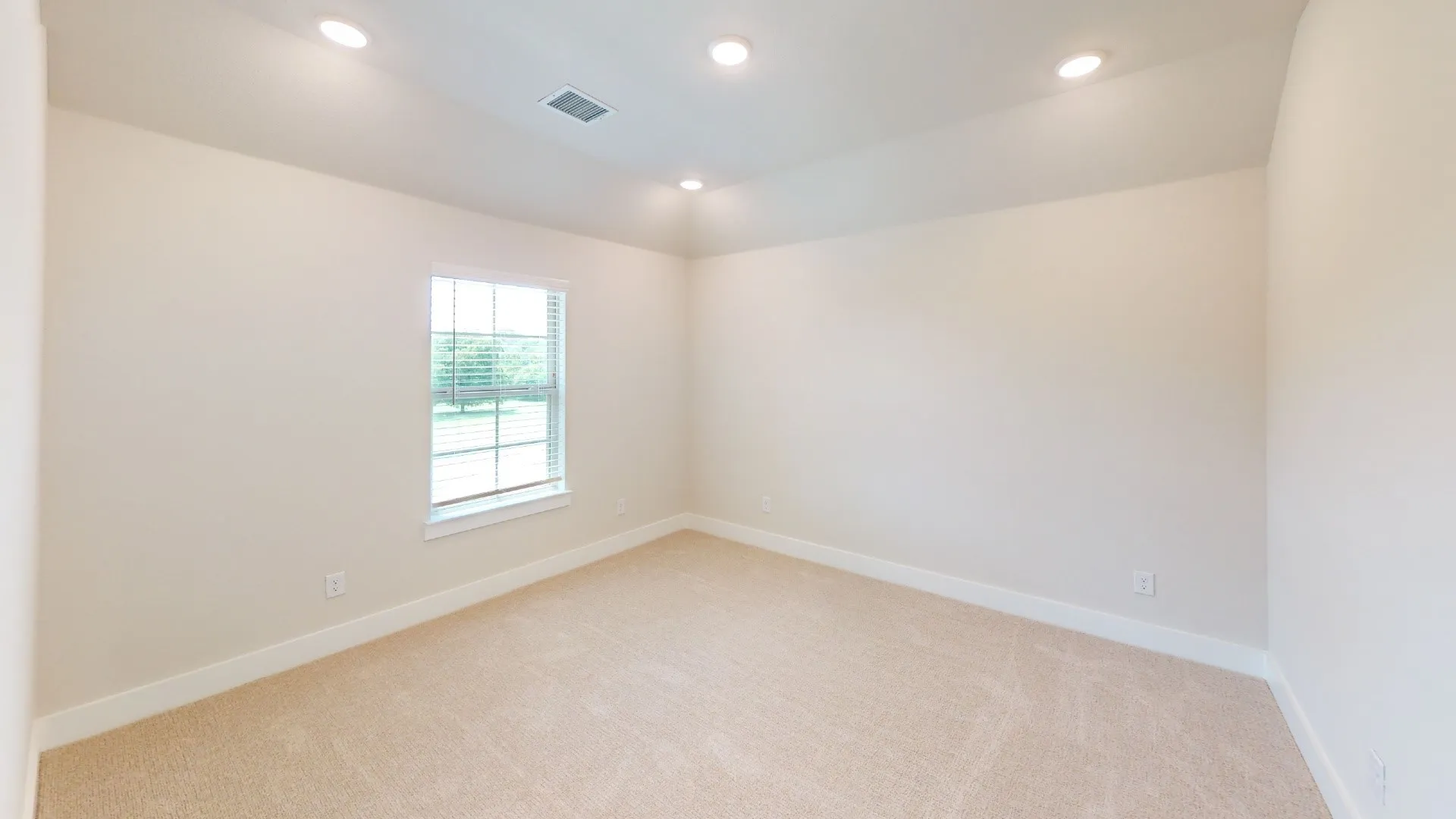Neutral-toned room featuring a single window with horizontal blinds, recessed ceiling lighting, and light-colored carpeting