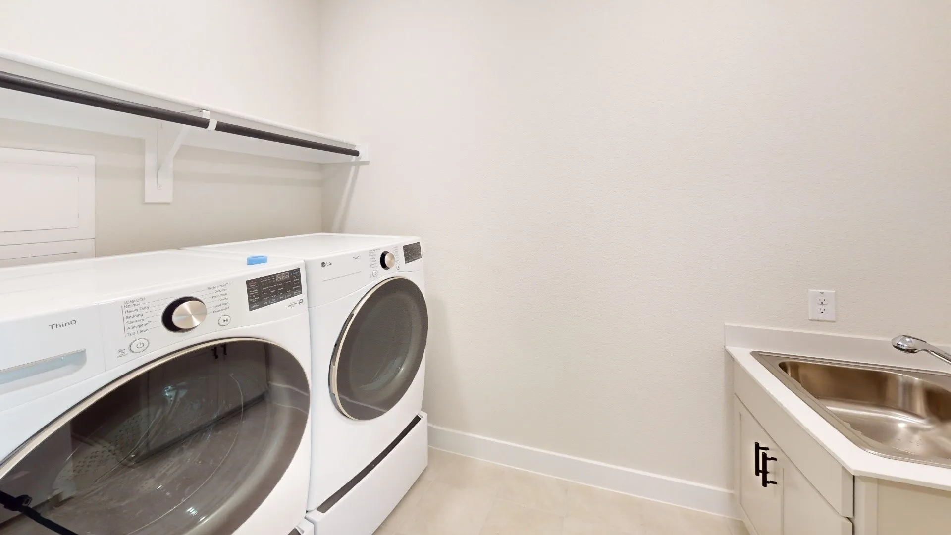 Laundry room featuring a utility sink, white cabinetry with black hardware, and an overhead shelf with a hanging rod