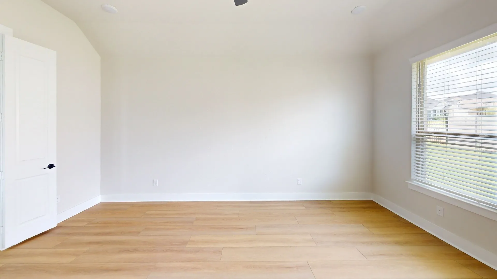 Bright room featuring wood-finish flooring, vaulted ceiling, recessed lighting, and a large window with horizontal blinds