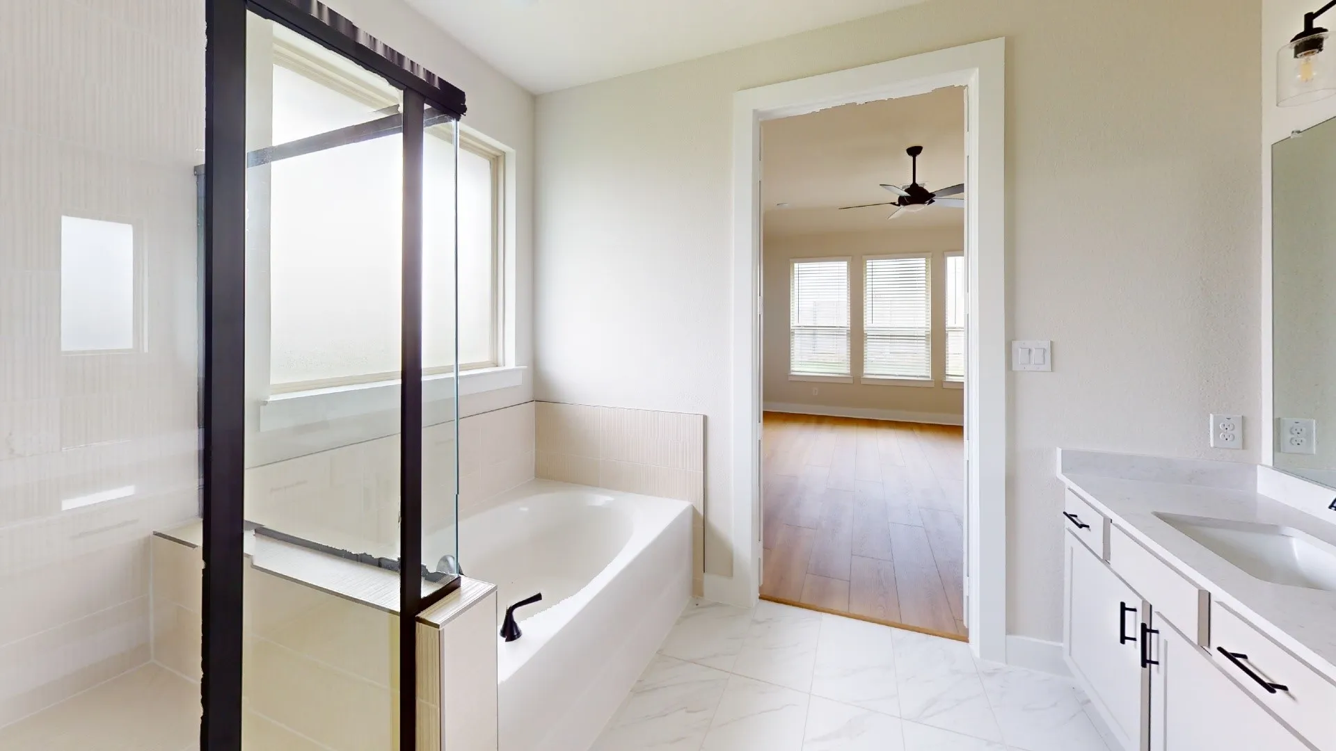 Bathroom featuring a built-in tub with matte black fixtures, a glass-enclosed shower with a bench, and a dual vanity with a white countertop