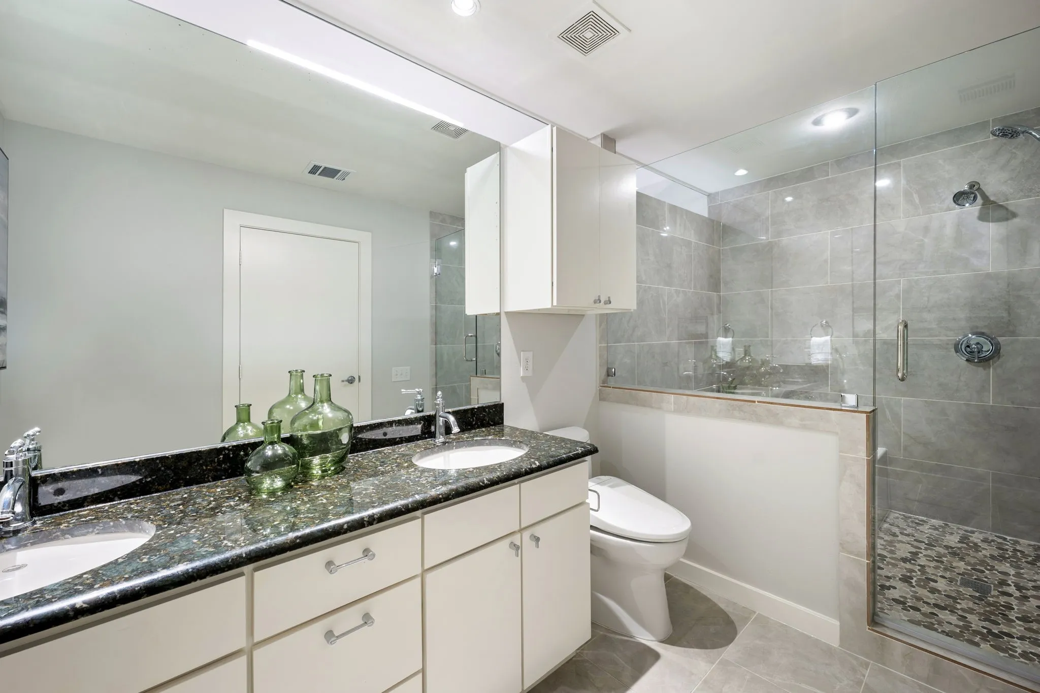 Dual vanity with undermount sinks, speckled dark countertop, and chrome fixtures