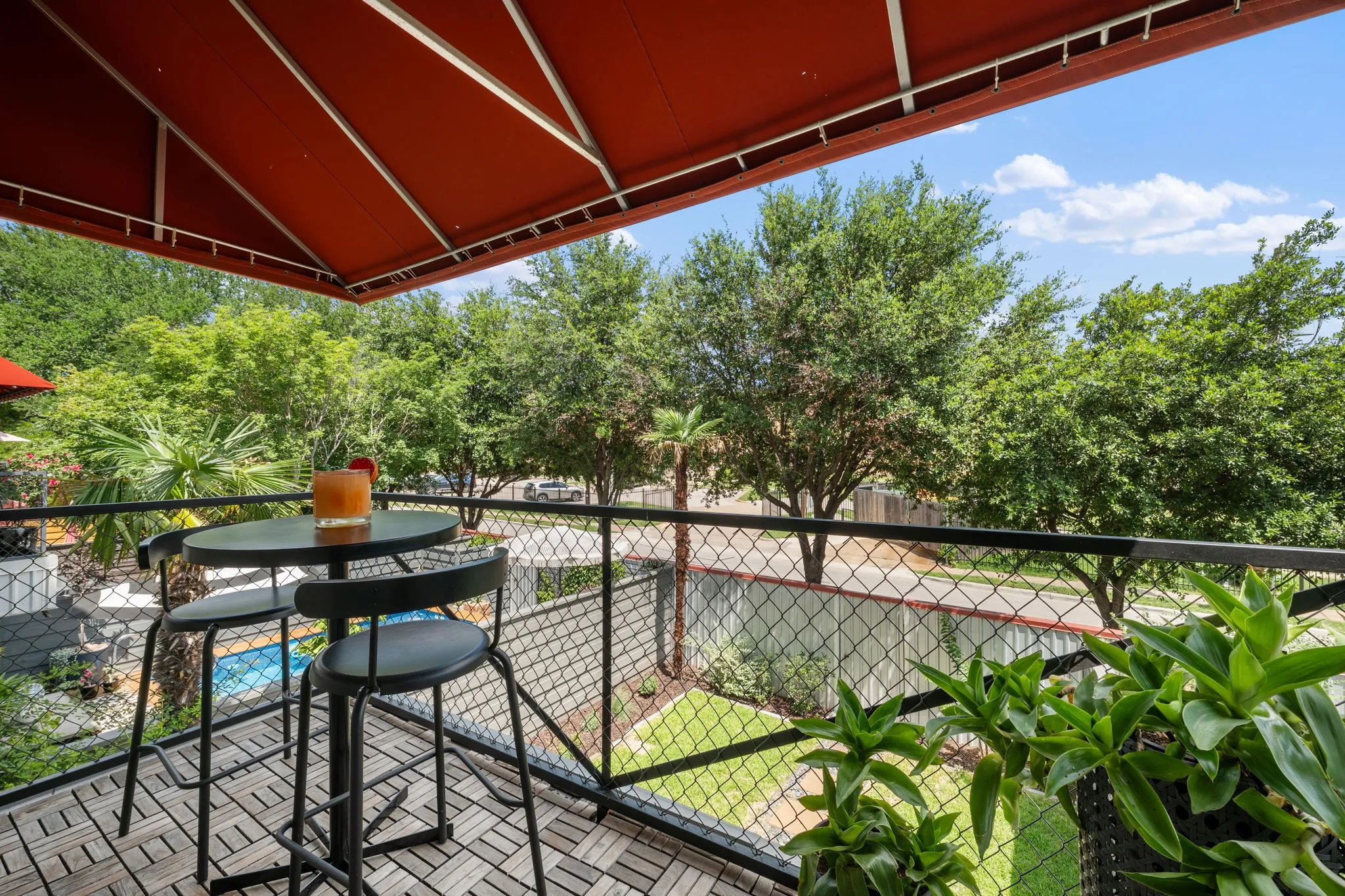 Outdoor patio with a red retractable awning and wood-finish tile flooring
