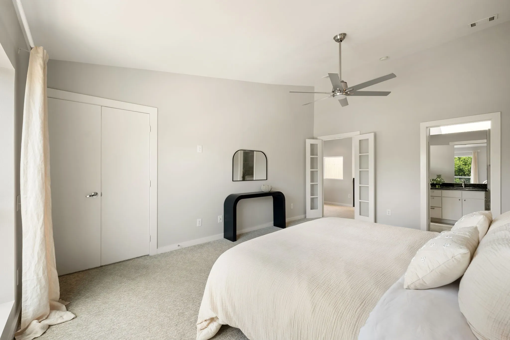 Vaulted ceiling featuring a ceiling fan, carpet flooring, double closet doors, and French doors leading to an additional space