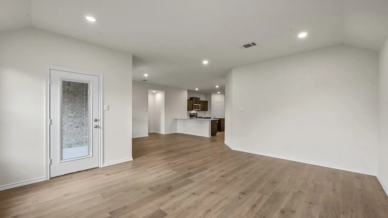 Open-concept room featuring wood-finish flooring, recessed lighting, and a white paneled door with privacy glass