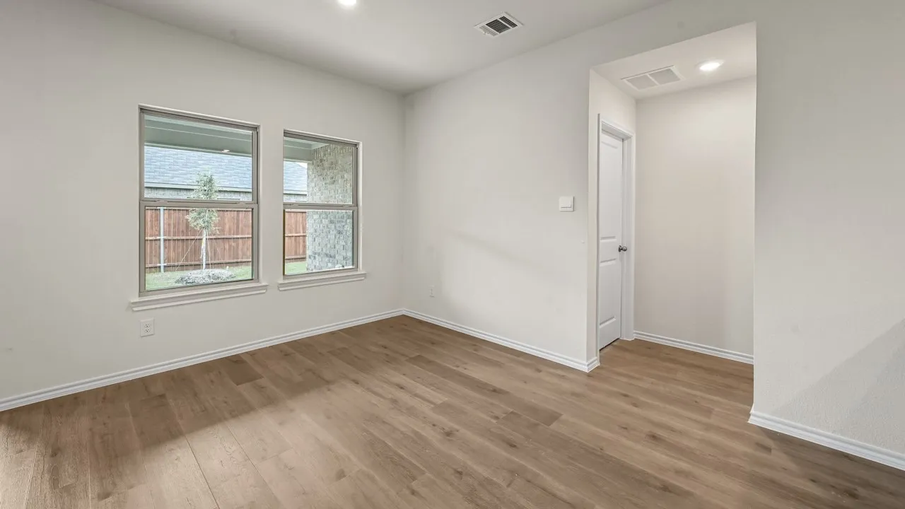Spacious room featuring wood-finish flooring, white baseboards, and two large windows